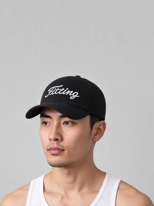 A man wearing a black FITTING baseball cap with white embroidered logo on a light grey background