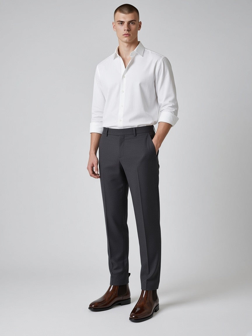 FITTING mahogany leather Chelsea boots worn by a man in a white shirt and charcoal trousers against a grey background