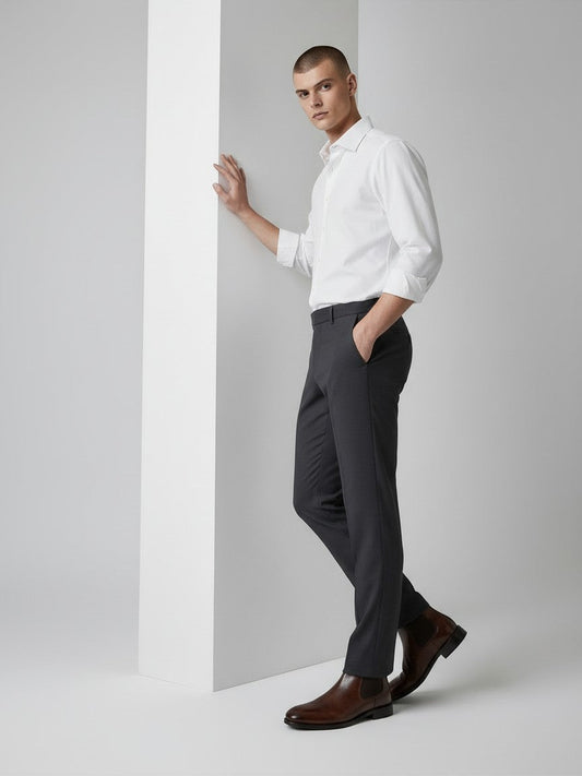 A man wearing FITTING mahogany leather Chelsea boots with a white shirt and dark trousers in a studio setting.