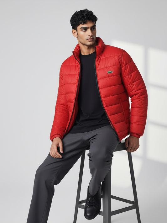 FITTING red lightweight quilted puffer jacket with high neck collar worn by a man sitting on a stool